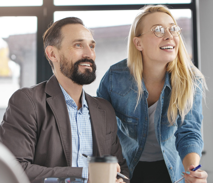Two business partners look attentively at presentation of full screen, being glad meet together, focused into distance, going to have coffee break. Creative copywriters collaborate for common project